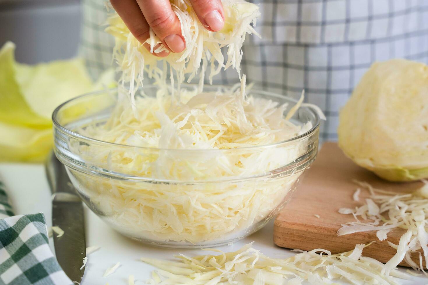 The girl pours chopped cabbage into a glass bowl. Cooking a delicious and healthy salad. Close-up. Selective focus. photo