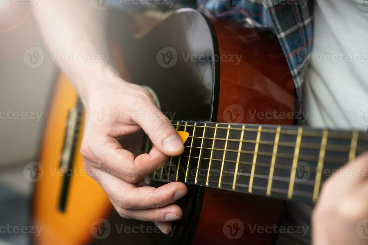 A young man with mediator playing guitar. Close-up. Selective focus. photo