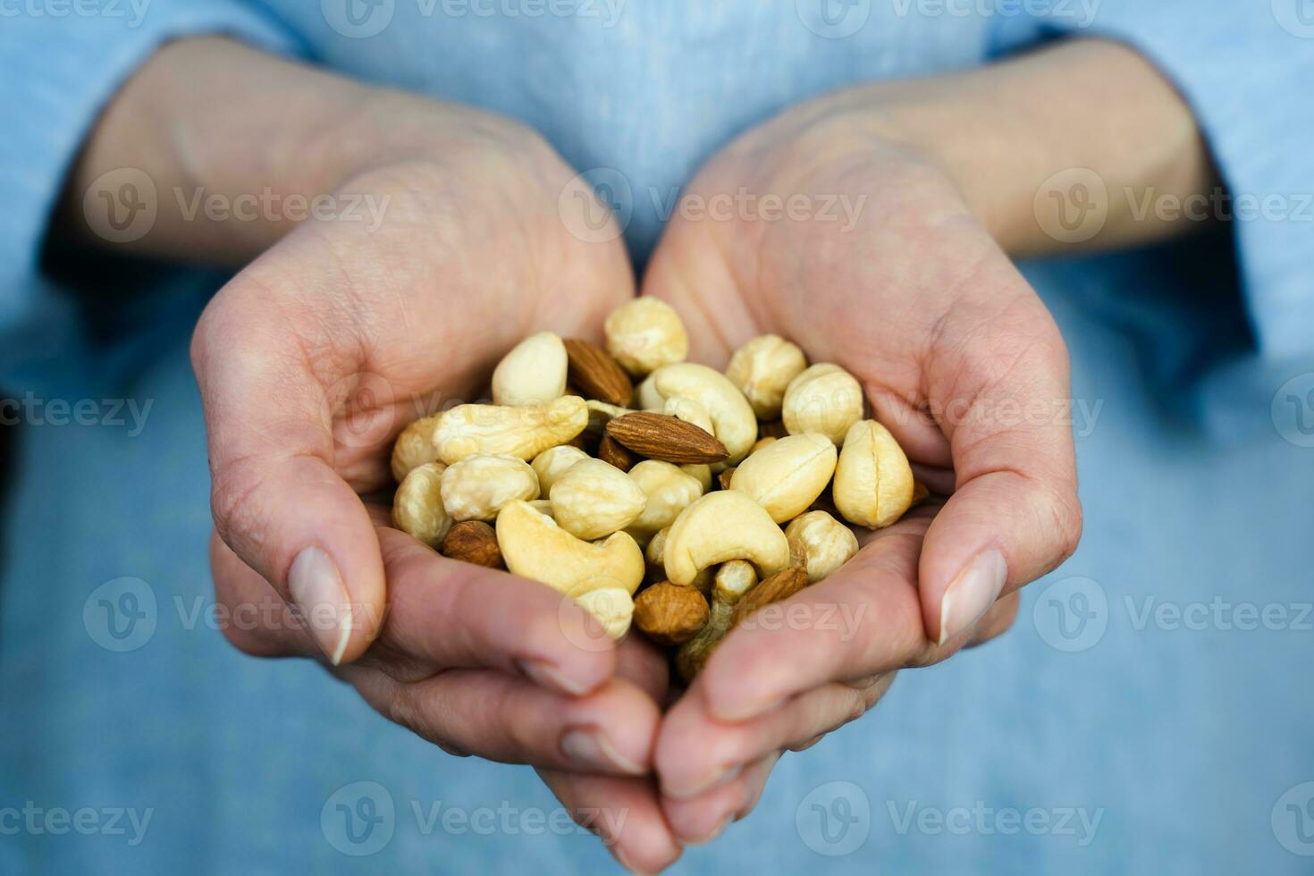 Close-up of woman's hands holding a handful a mixed of nuts. Healthy food concept. Selective focus. photo