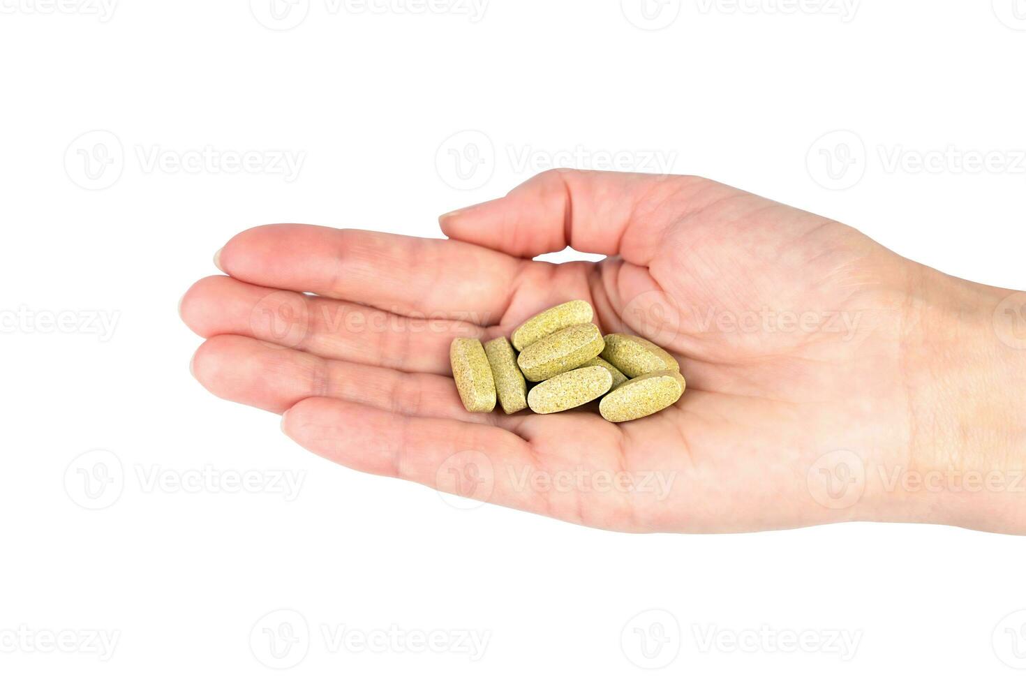 A womens hand holds a green pills isolated on white background. Healthy lifestyle concept. Close-up. photo