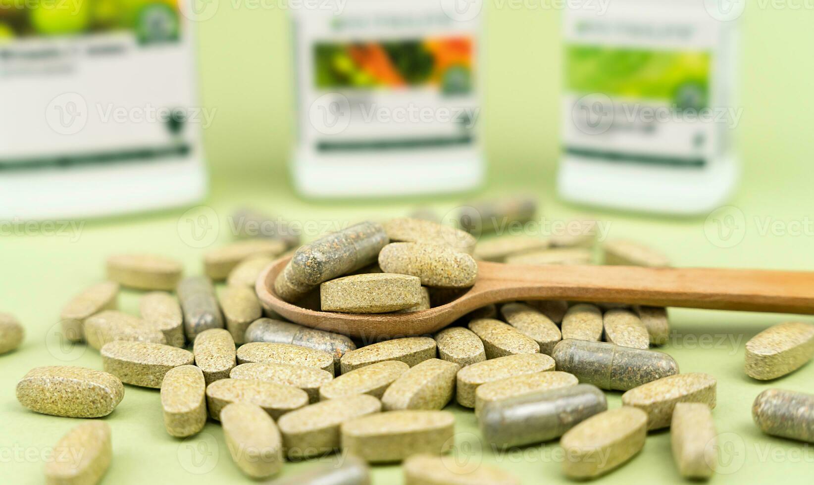 Natural vitamins and supplements in a wooden spoon on a green background. Close-up. Selective focus. photo