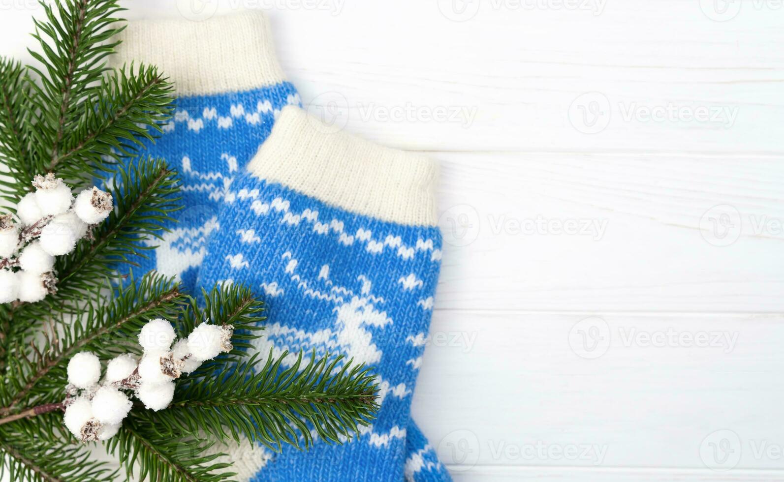 Festive flatlay composition with a fir branches, Christmas decor and knitted socks on a white wooden background. Top view. Copy space. Selective focus. photo