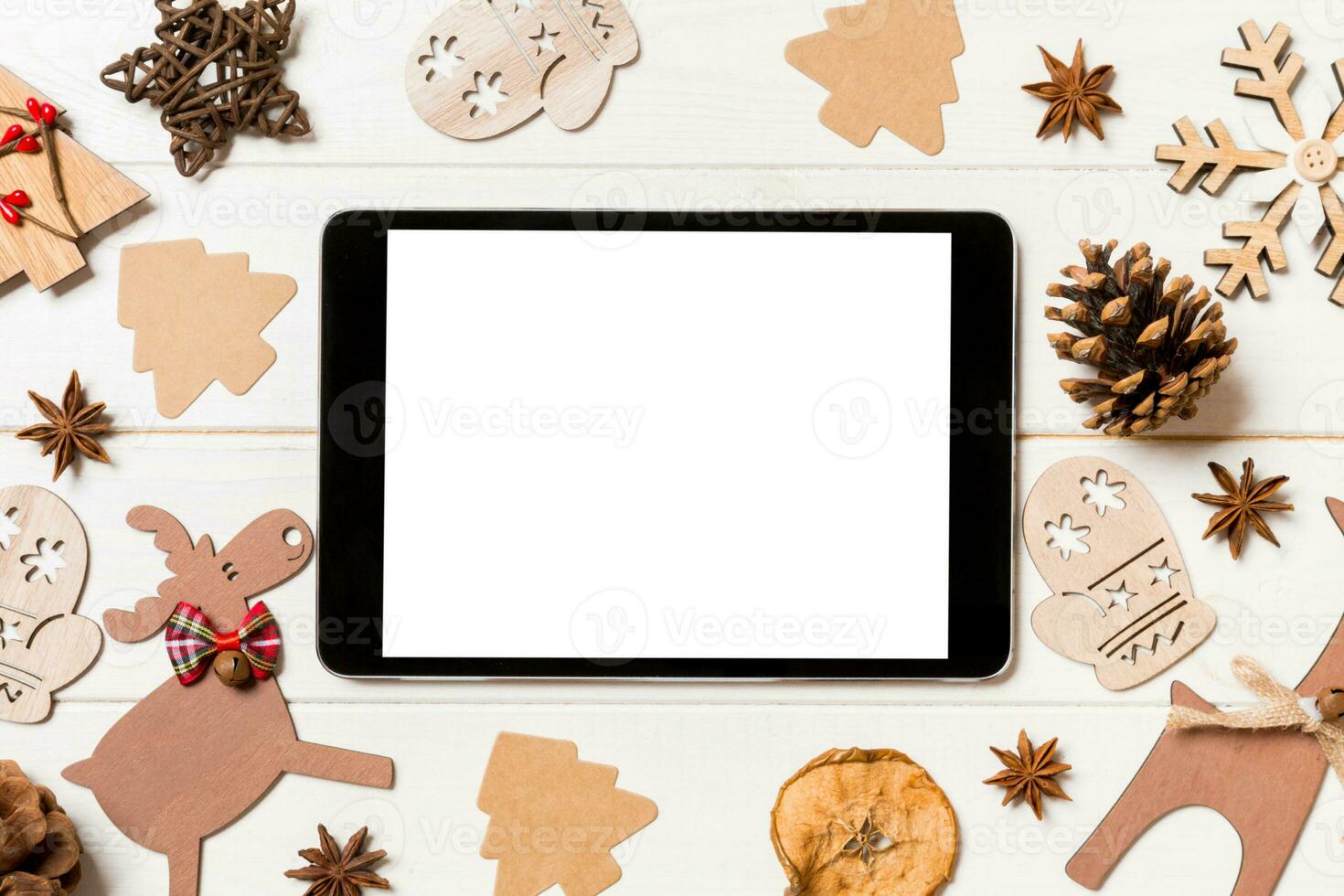 Top view of tablet on holiday wooden background. New Year decorations and toys. Christmas concept photo