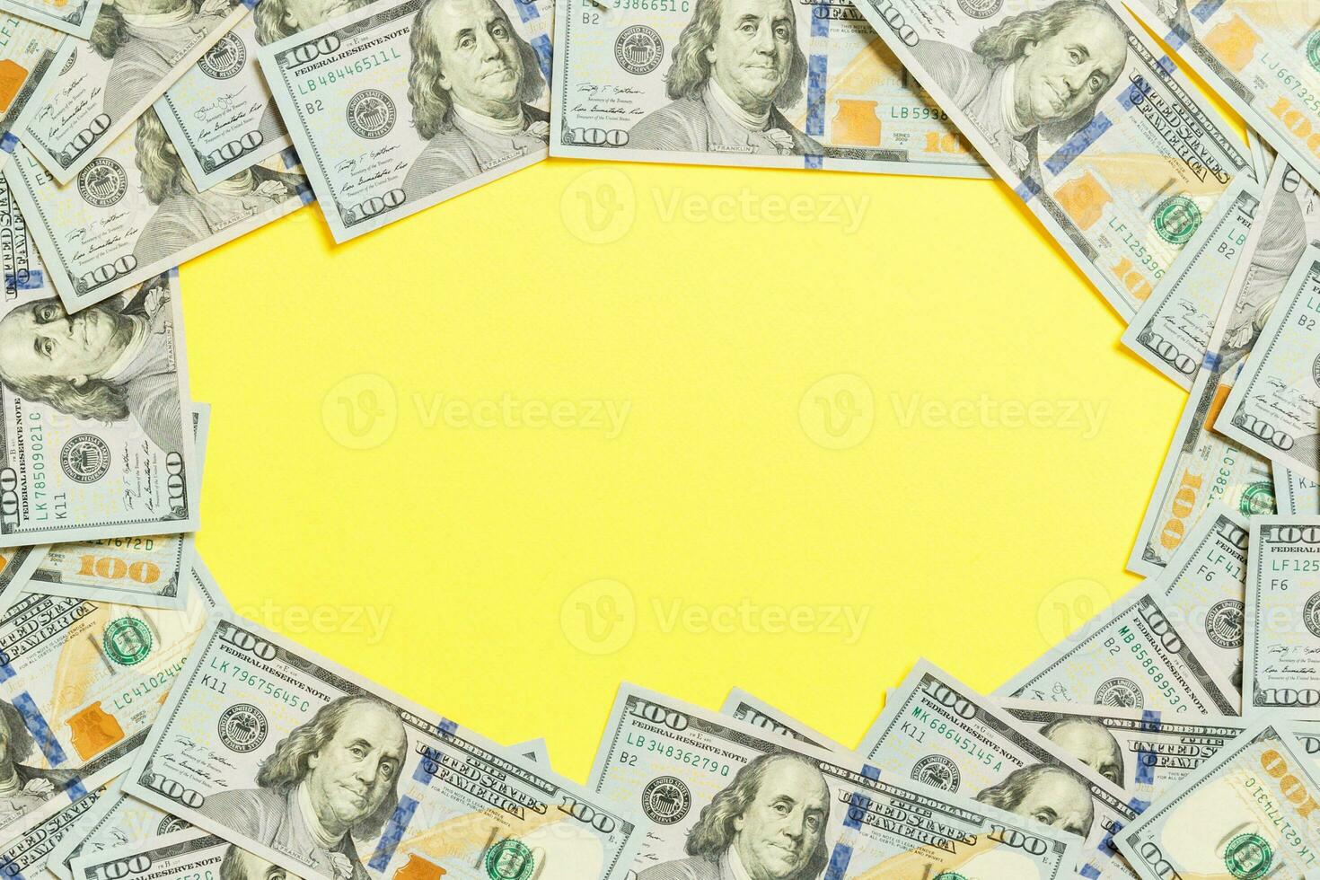 Frame of one hundred dollar bills with empty space for your design. Top view of business concept on yellow background with copy space photo