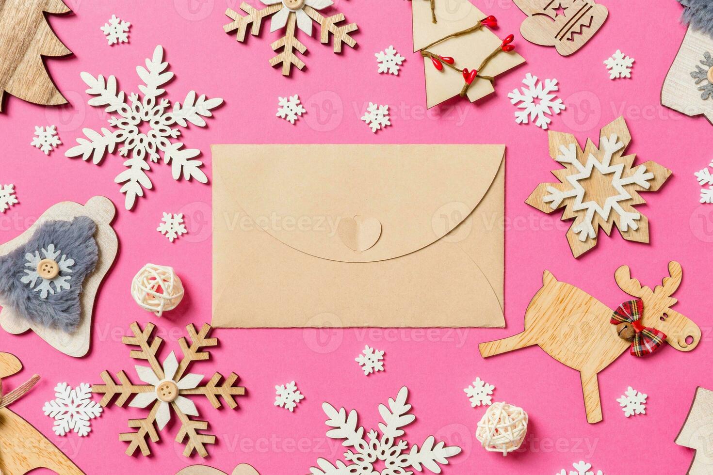 Top view of craft envelope on pink background made of holiday decorations and toys. Christmas ornament concept photo