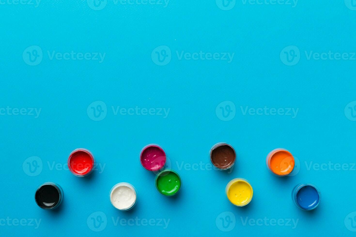 jars with gouache of different colors on Colored background. hobby painting. Top view with empty space. workplace for creativity. home teaching concept drawing photo