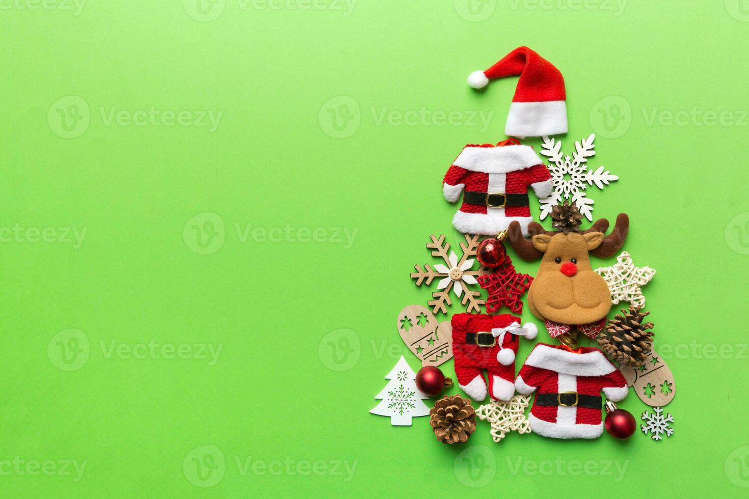 Christmas tree made from colored suit santa decoration on colored background, view from above. New Year minimal concept with copy space photo