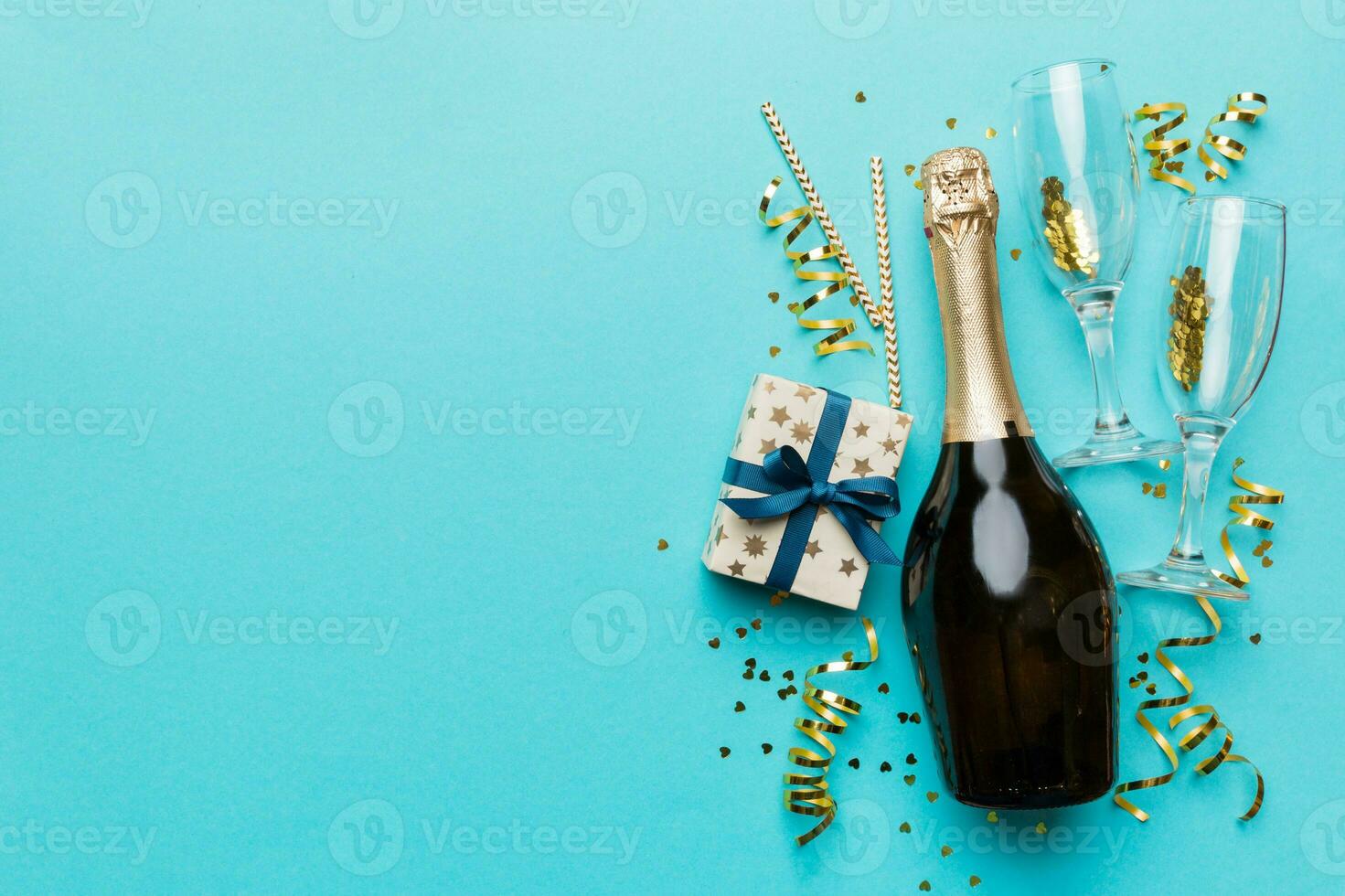 Bottle of champagne with colored glitter, confetti and gift box space for text on colorfull background, top view. Hilarious, christmas and birthday celebration photo
