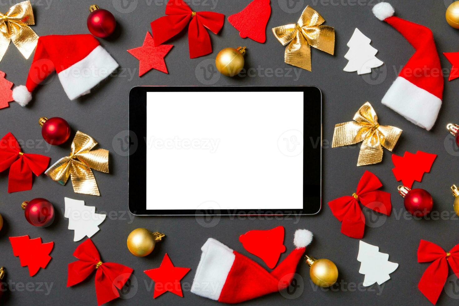 Top view of digital tablet on black background with New Year toys and decorations. Christmas time concept photo