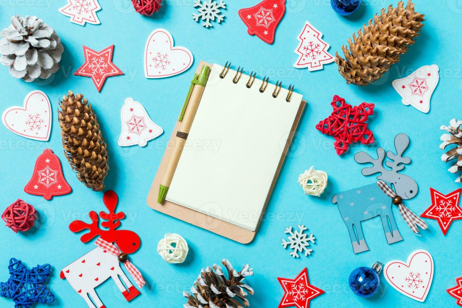 Top view of notebook surrounded with New Year toys and decorations on blue background. Christmas time concept photo