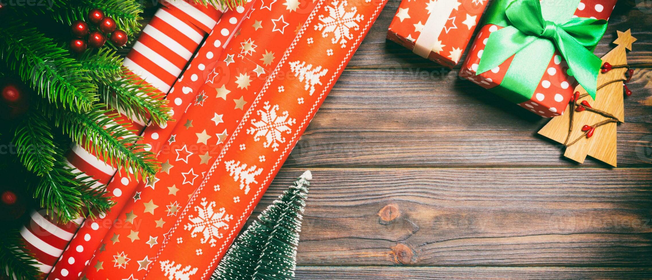 Top view of Christmas background made of fir tree, rolled wrapping paper and other decorations on wooden background. Banner New Year holiday concept with copy space photo