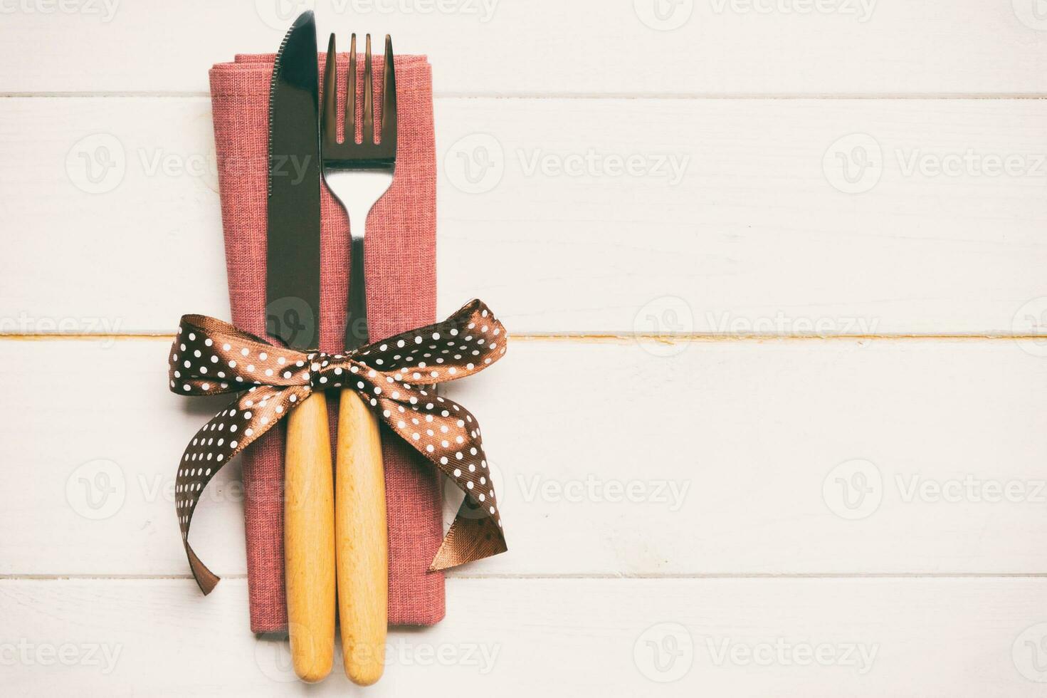Top view of fork and knife on napkin on wooden background. Different christmas decorations and toys. New Year dinner concept with empty space for your design photo