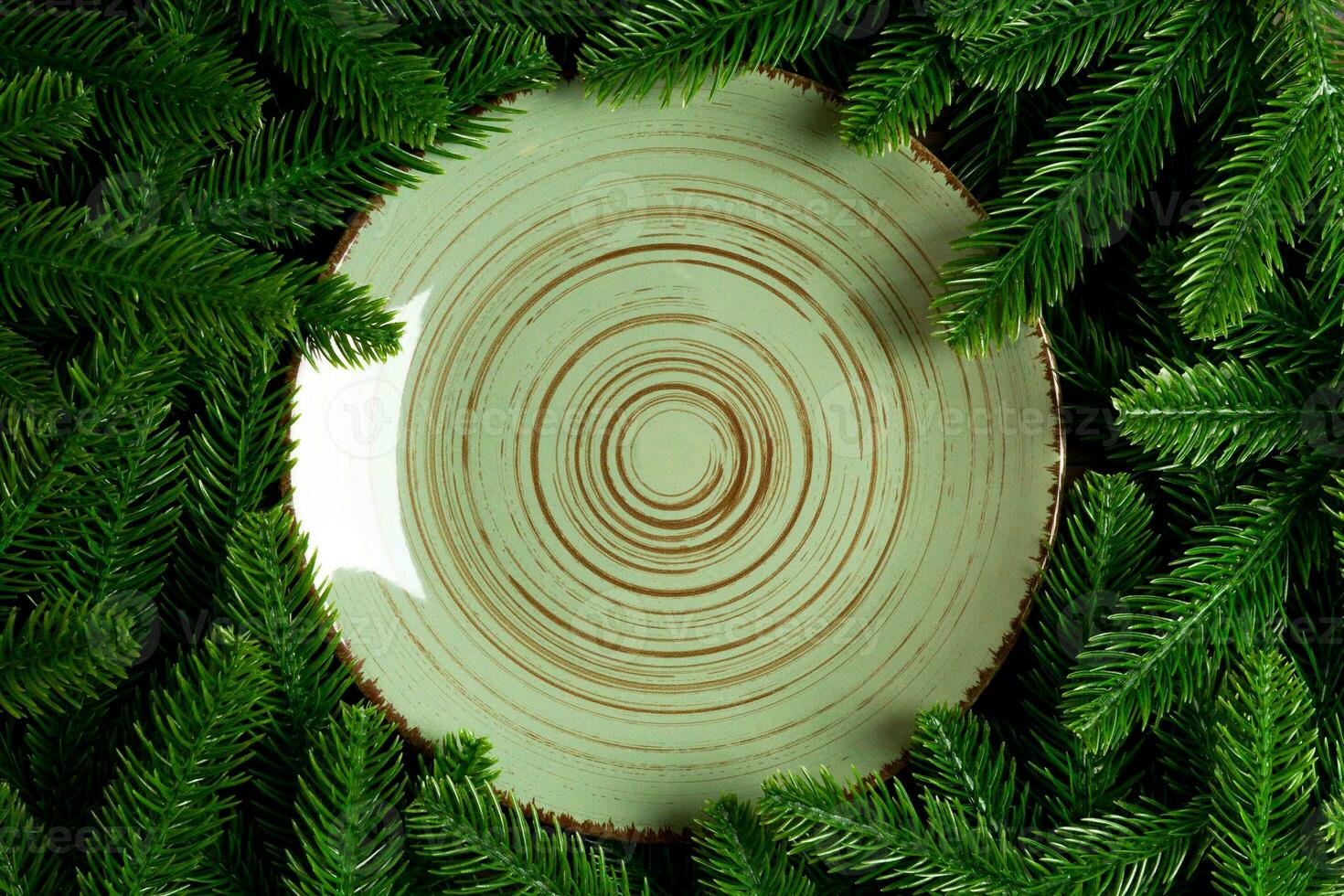 Top view holiday plate among green fir tree branches. Christmas dinner with copy space photo