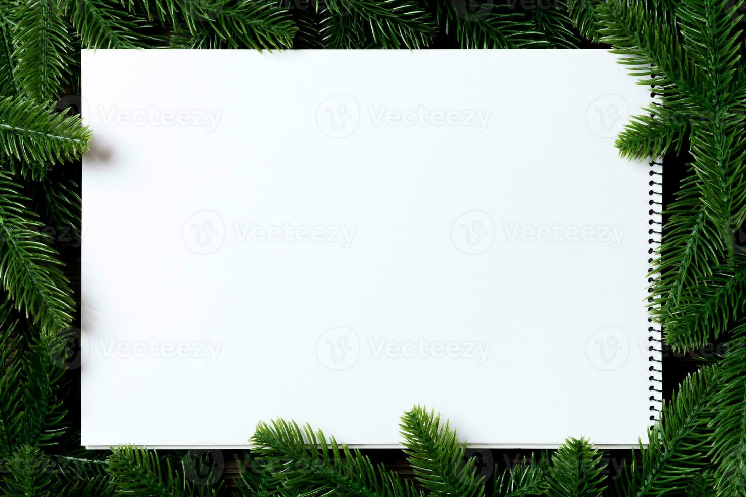 Top view of notebook decorated with a frame made of fir tree on wooden background. New Year time concept photo