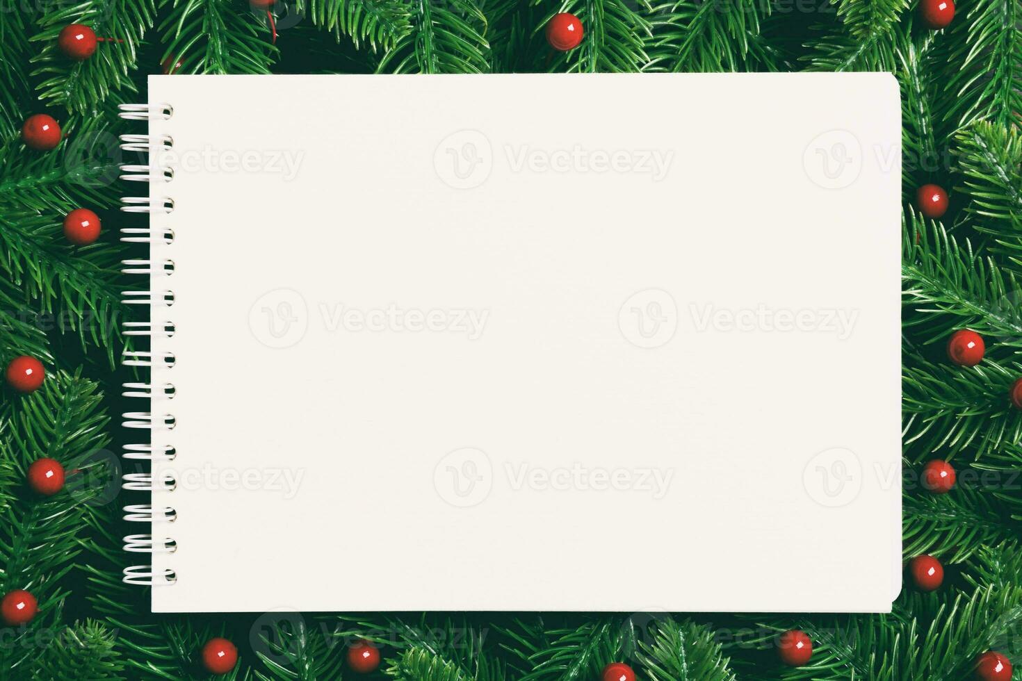 Top view of notebook decorated with a frame made of fir tree on wooden background. New Year time concept photo