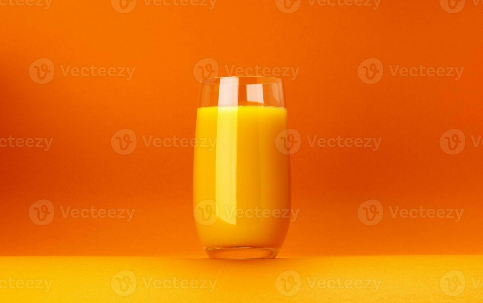 Glass of orange juice isolated on orange background with copy space photo