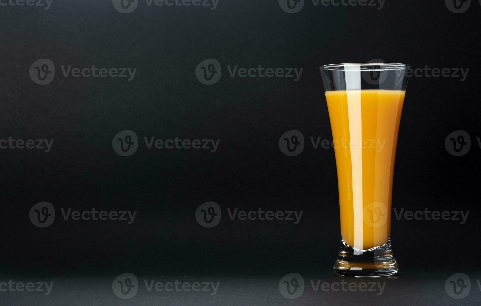Glass of orange juice isolated on black background with copy space for text, fresh citrus cocktail photo