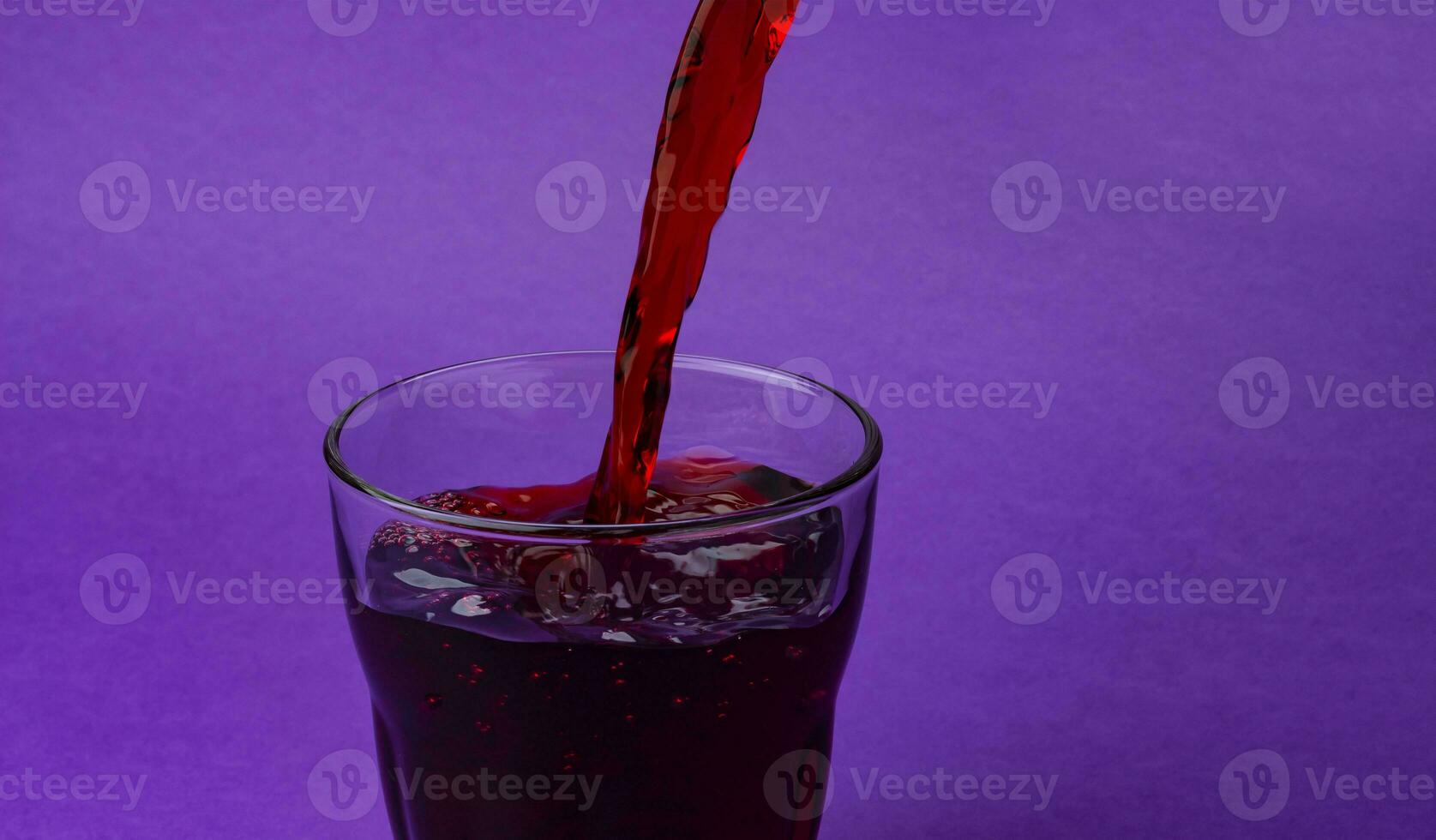 Cherry juice pouring into glass, isolated on purple background, with copy space photo