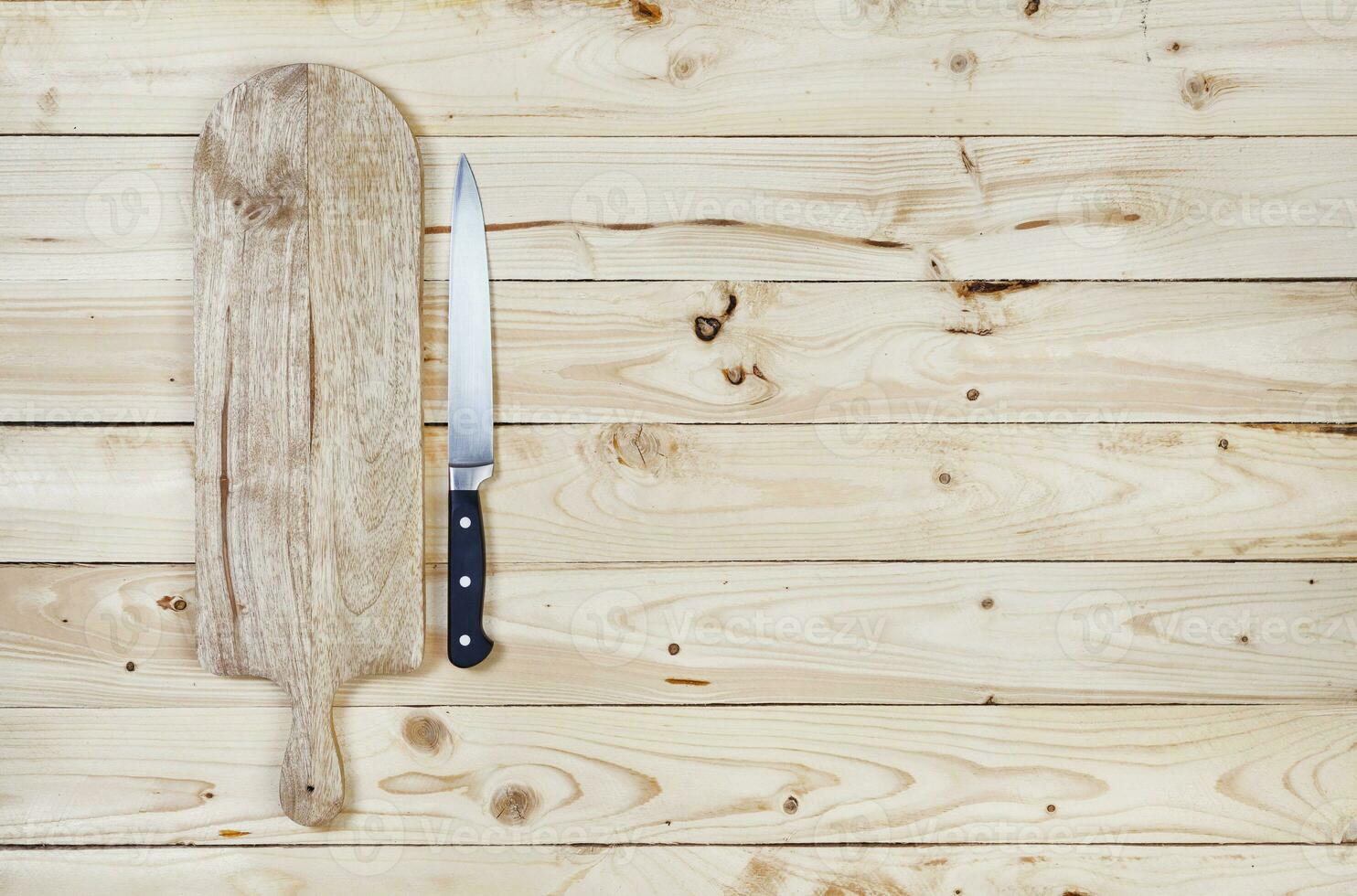 Cutting board with knife on wooden table. Top view photo