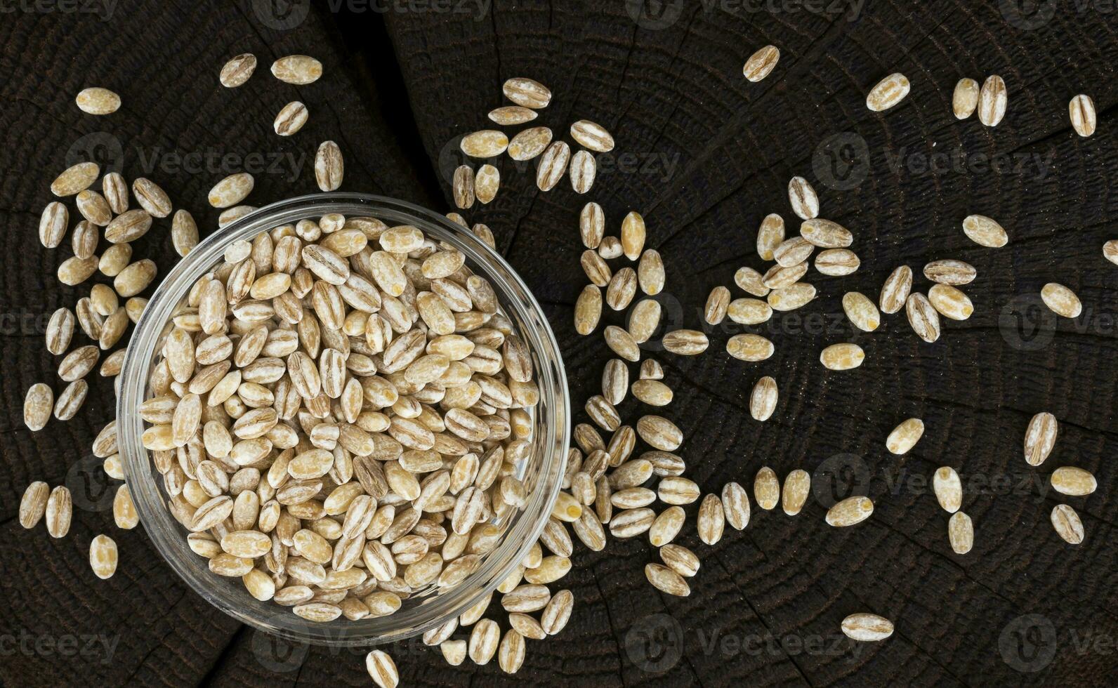 Bowl of pearl barley on black background. Top view photo