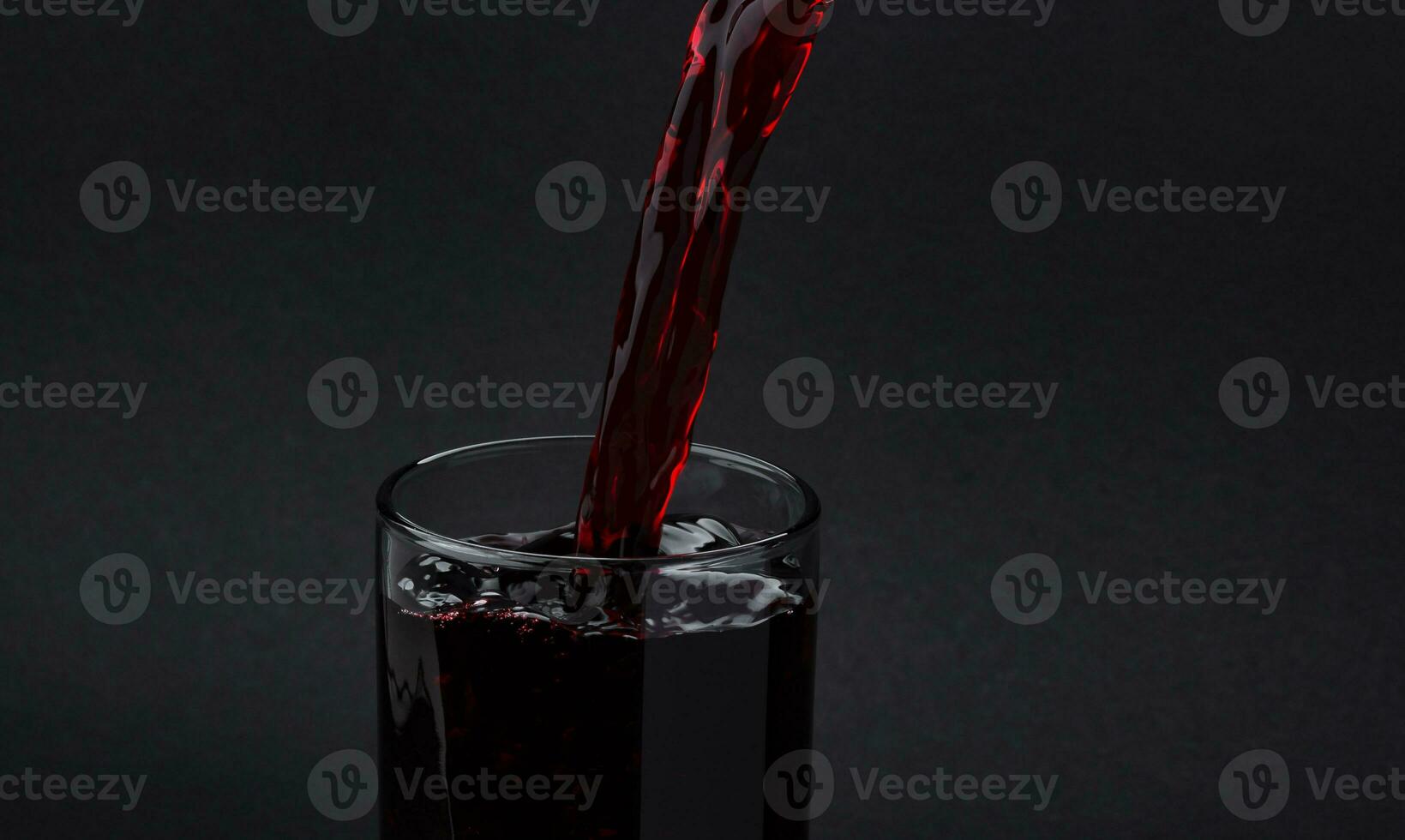 Cherry juice pouring into glass, isolated on black background photo