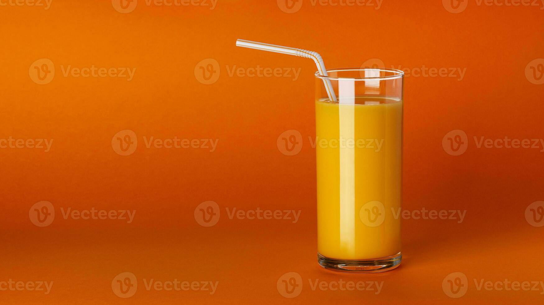 A glass of orange juice on orange background with copy space photo