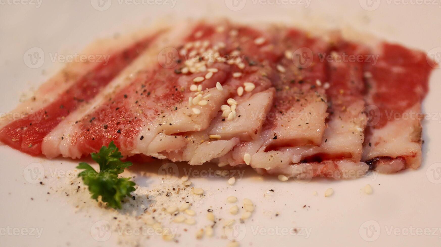 Slice of fresh beef or pork meat present in a white plate for grill, barbeque, and hot pot. Japanese Wagyu Yakiniku beef slice. photo