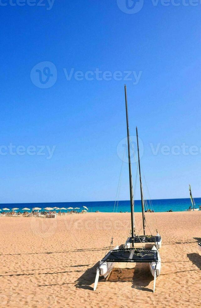 a sailboat is docked on the beach in front of the ocean photo