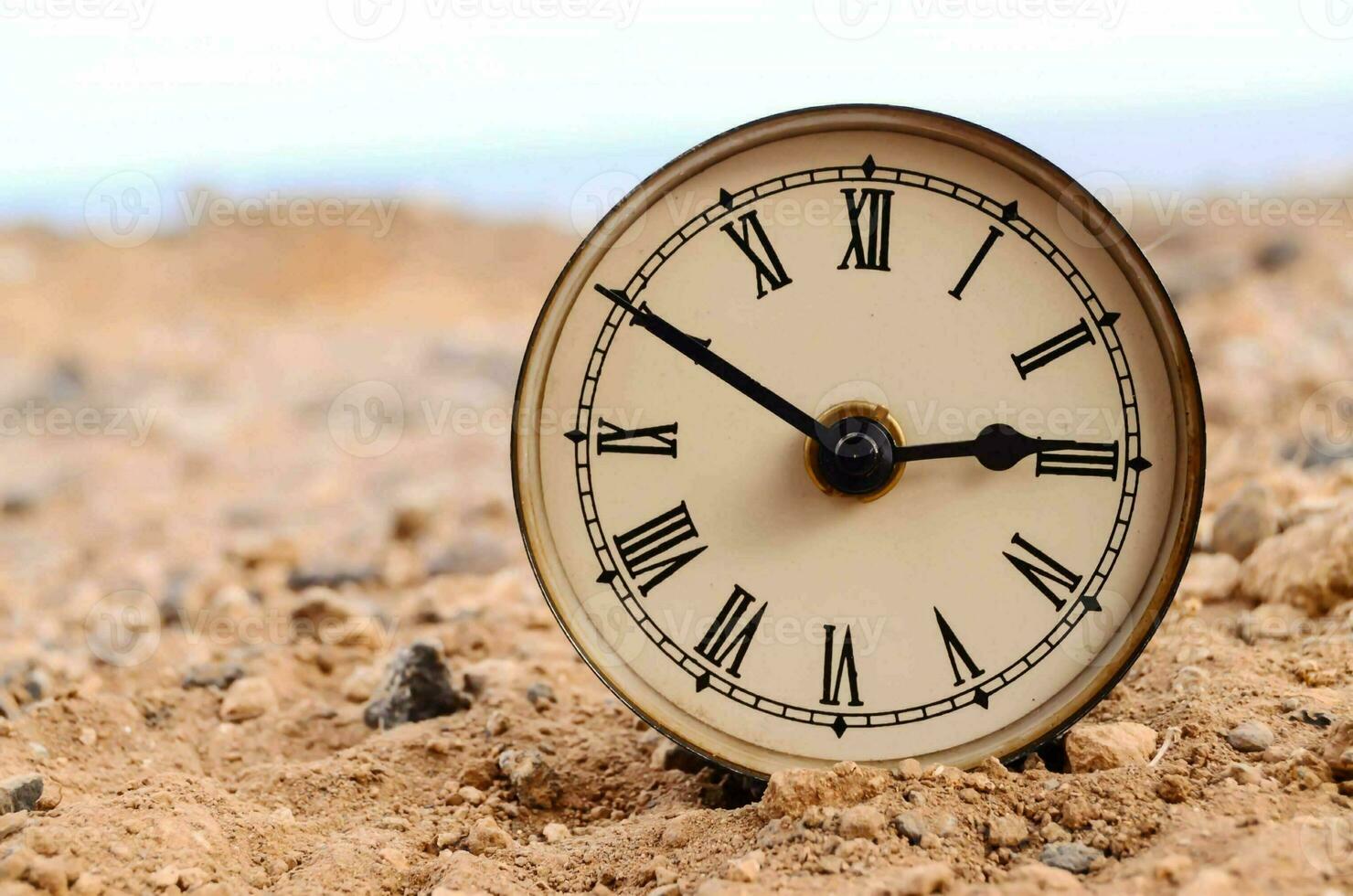 a clock is sitting on the ground in the desert photo