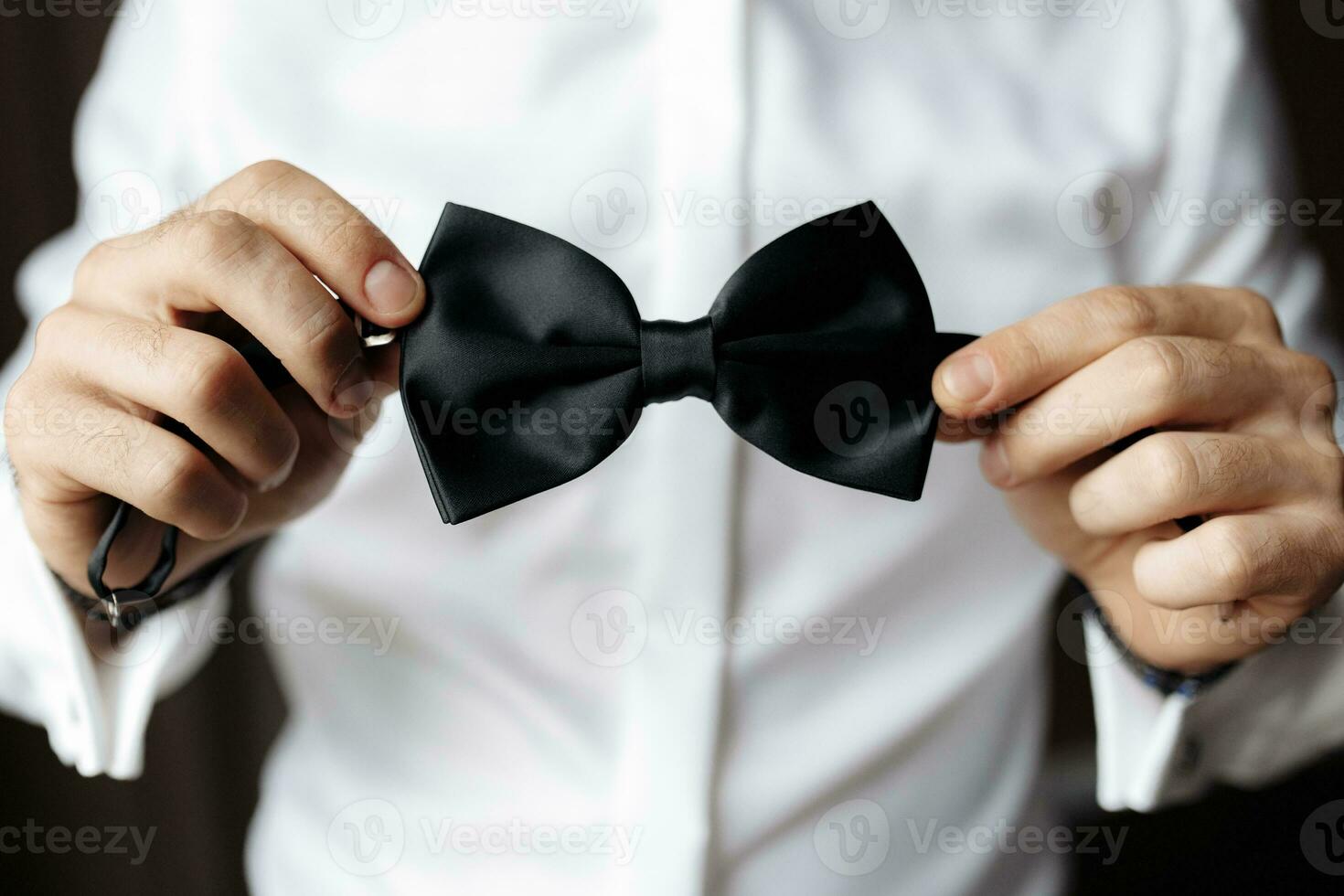 Close up view of man holding black bow tie in hands. Soft focus photo