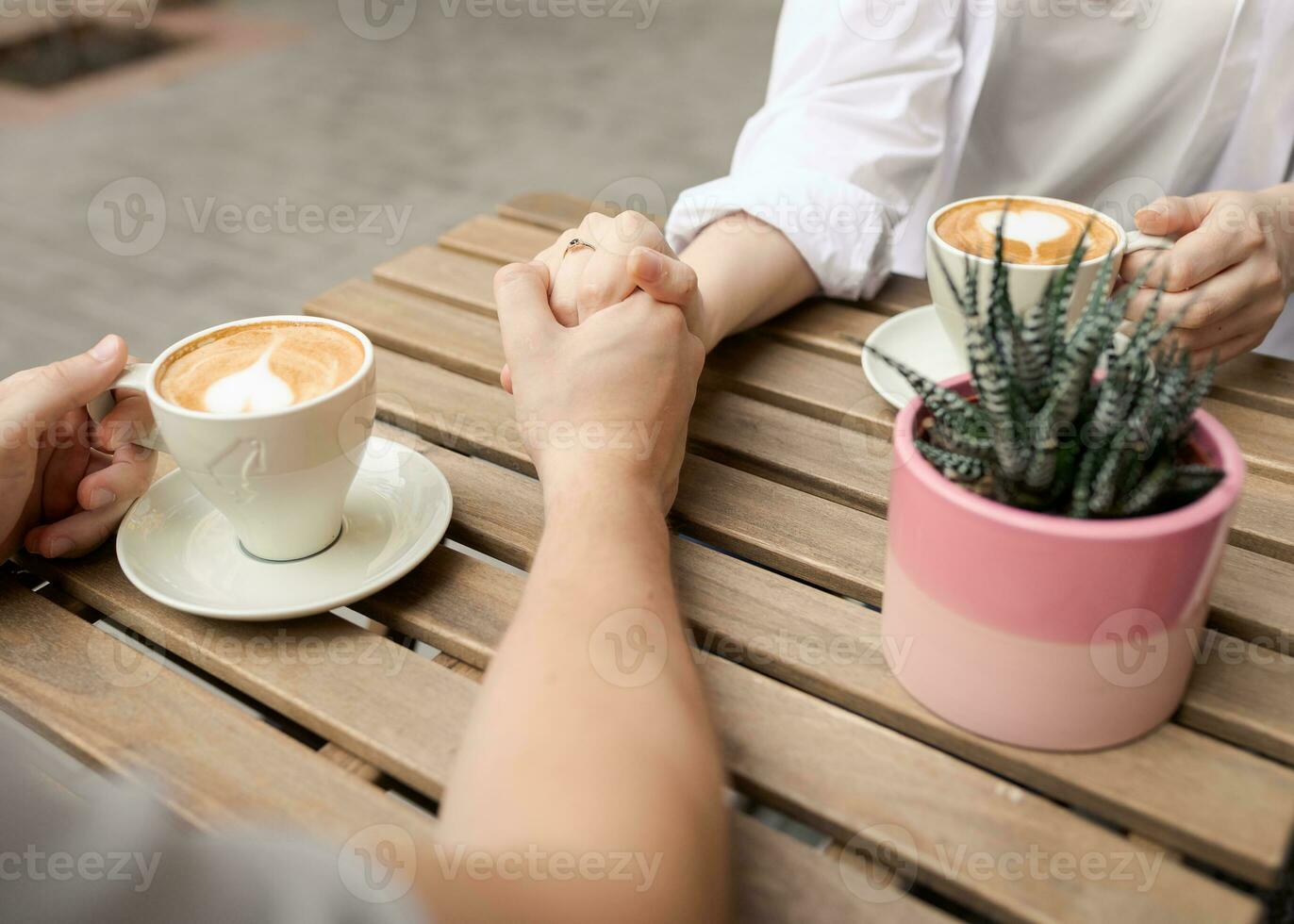 Couple holding hands and coffee outside closeup lateral top view. photo