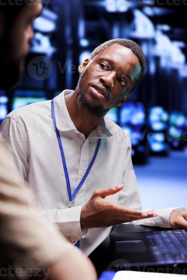 African american expert and colleague dealing with server room system failures. Computer scientists brainstorming ways to minimize data center equipment downtime and prevent crashes photo