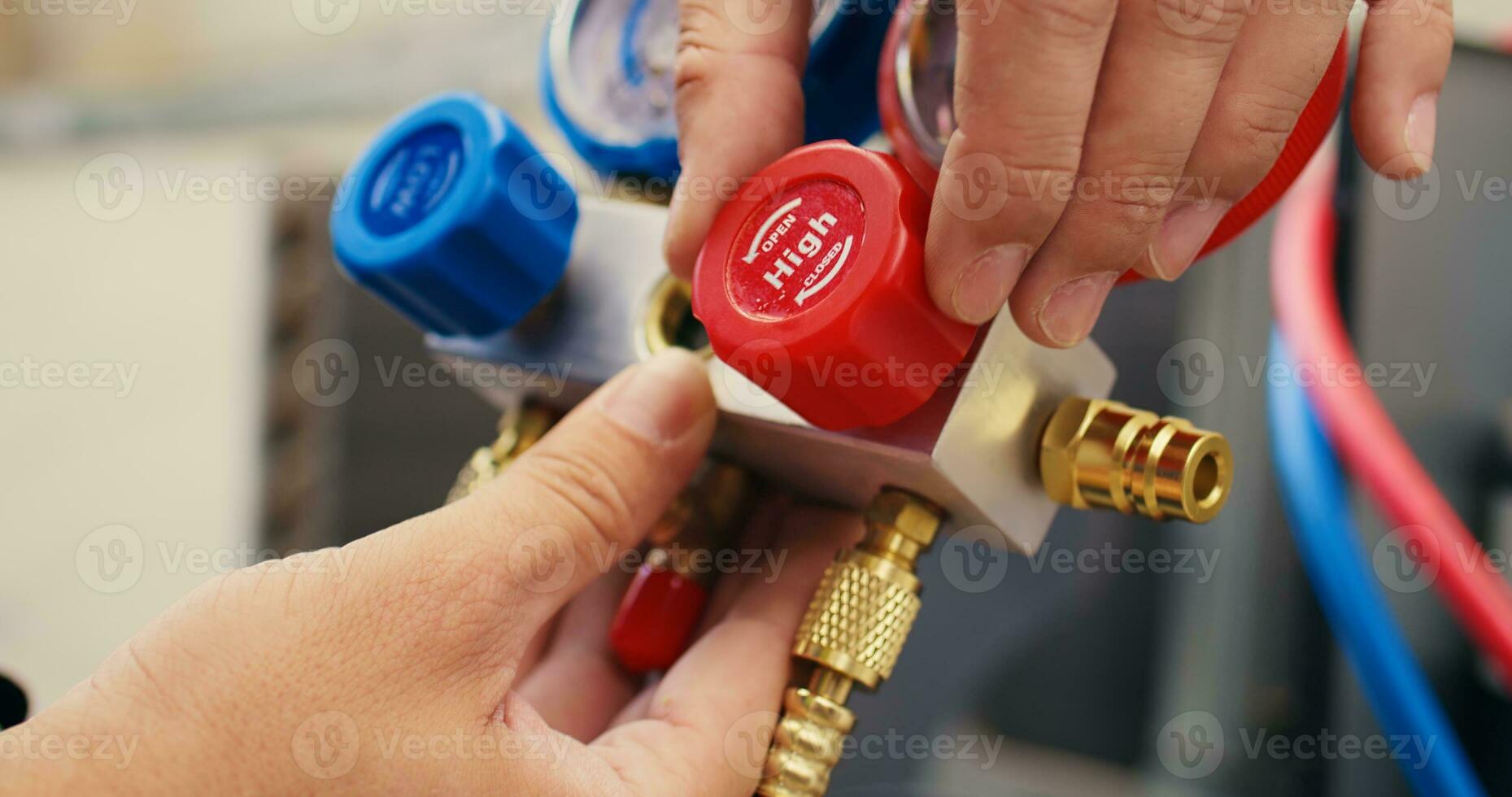 Extreme close up shot of repairman calibrating pressure measurement device during comissioned air conditioner troubleshooting. Worker turning on red and blue superheat and subcooling manometer knobs photo