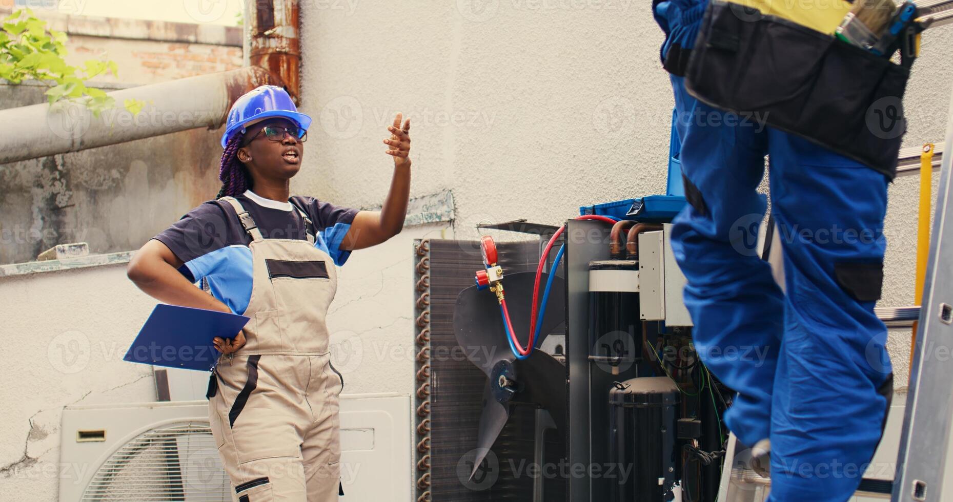 Diverse team of adept repairman brainstorming possible ways to recondition busted outdoor air conditioner. Knowledgeable professionals commissioned by home owner to patch up broken condenser photo