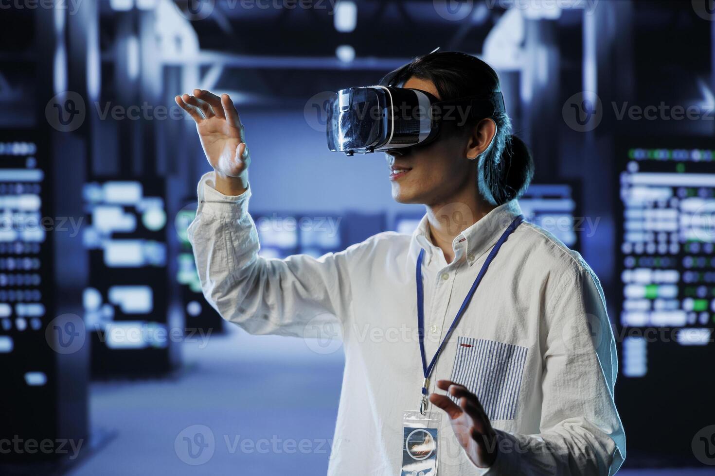 Admin in data center uses virtual reality to prevent system overload during peak traffic periods. Man with VR headset in server farm ensuring enough network bandwidth for smooth operations photo