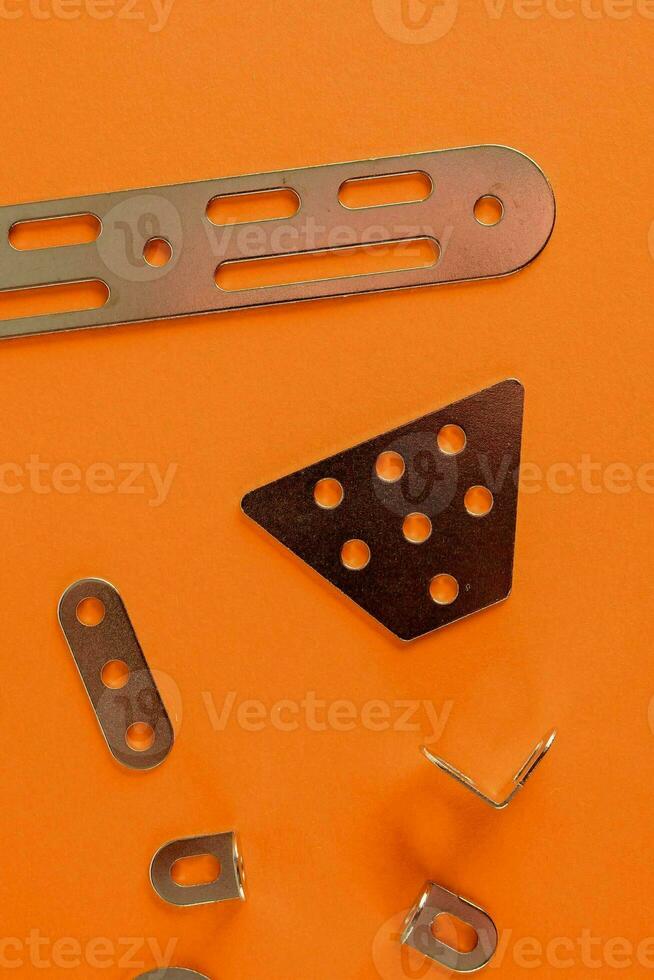 a pile of metal clips and screws on a orange surface photo