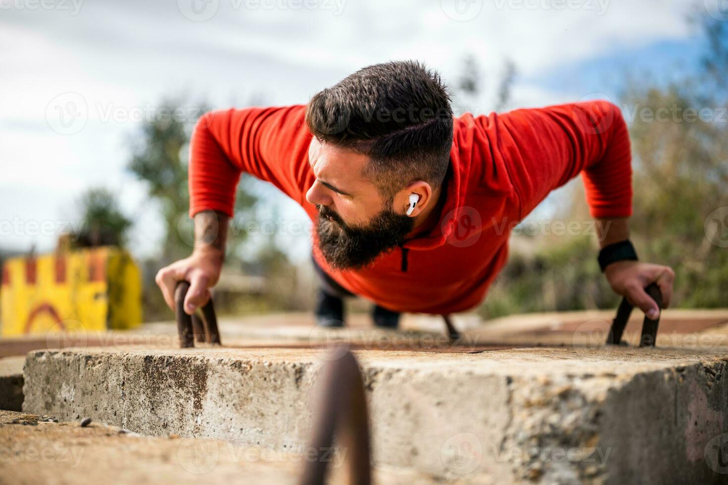 Young man is exercising outdoor. He is doing push-ups. photo