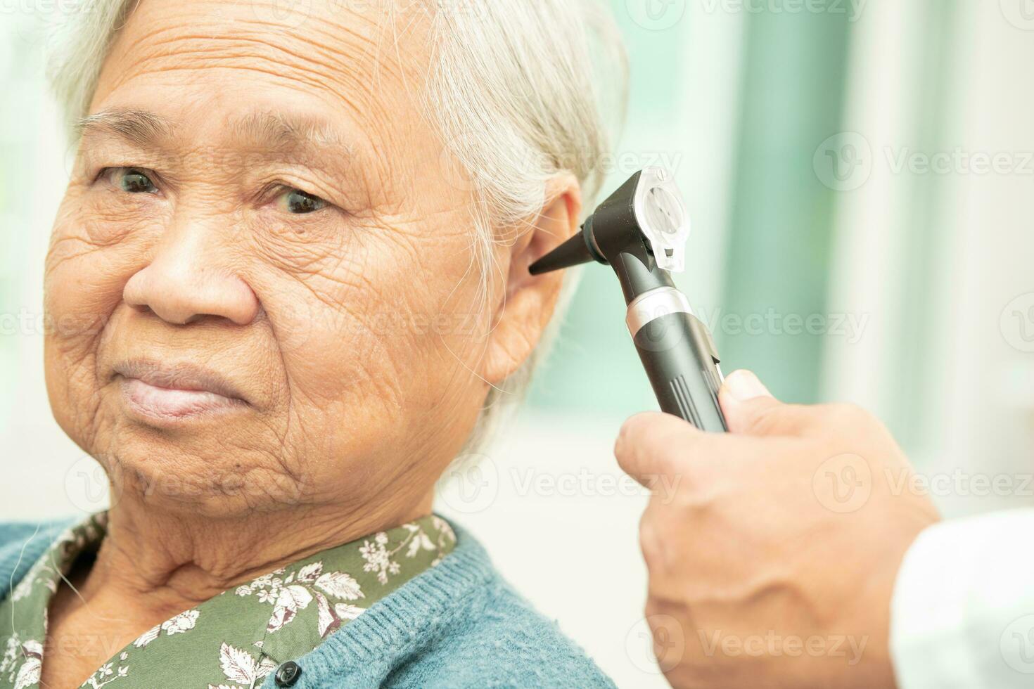 Audiologist or ENT doctor use otoscope checking ear of asian senior woman patient treating hearing loss problem. photo