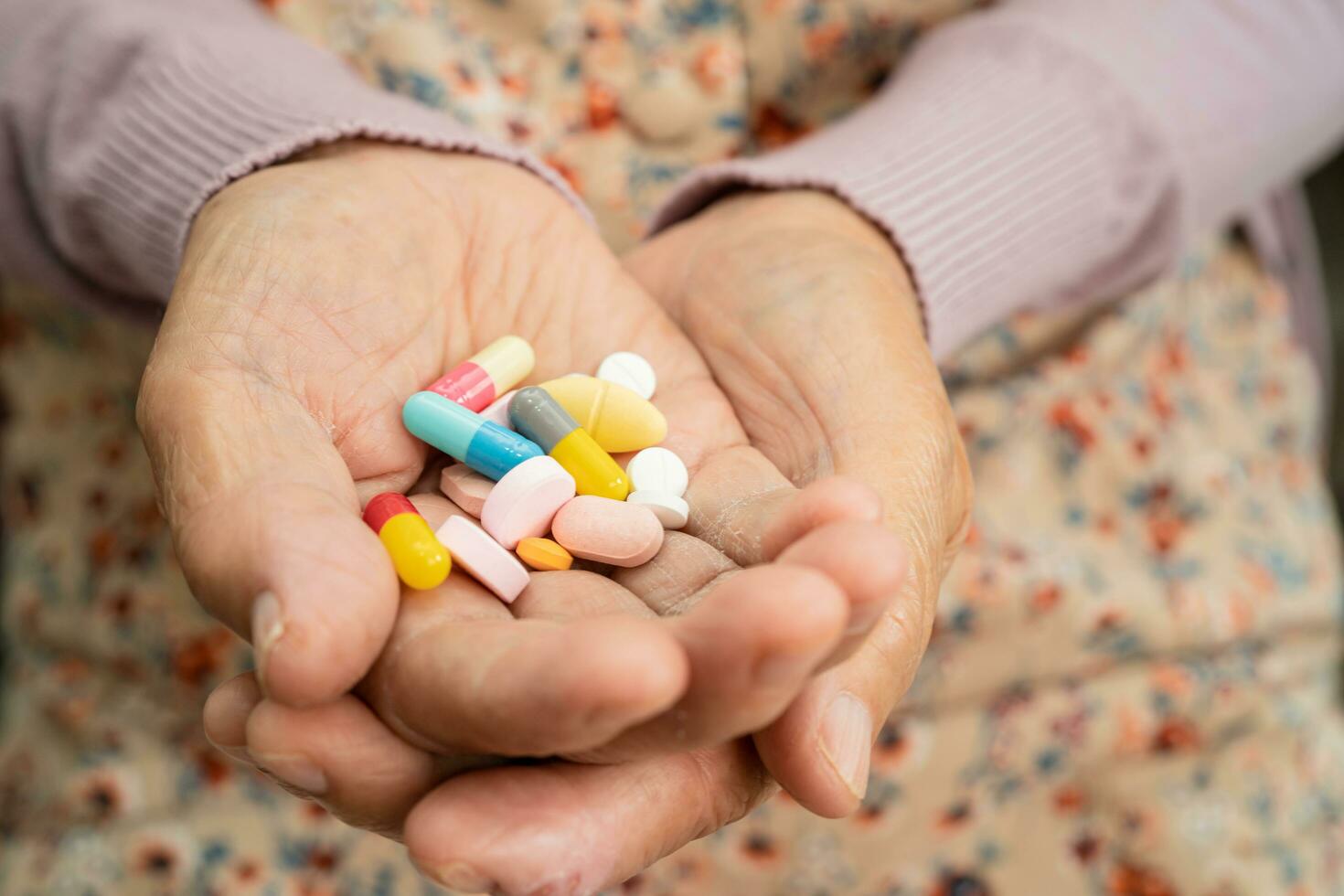 Asian senior woman patient holding antibiotics capsule pills  for treatment infection patient in hospital, Pharmacy drugstore concept. photo