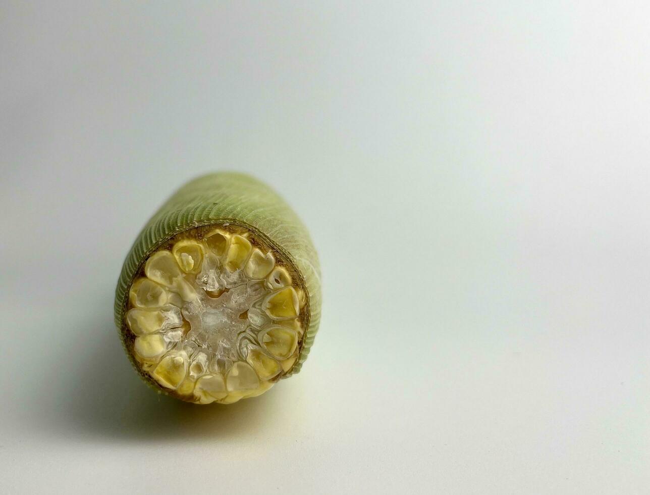 Yellow vegetable seed, sweet whole corn for cooking ingredients wrapped in corn leaves. Upper top part from front view. Raw food photography isolated on plain background. Jagung image with copy space. photo