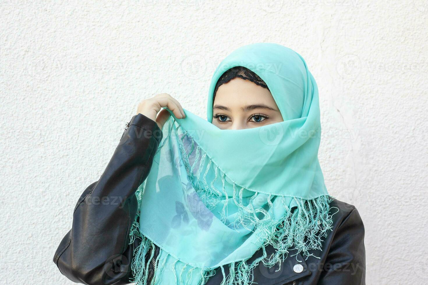 de cerca retrato de hermosa iraní niña con azul ojos. atractivo musulmán mujer en hijab cubierta su cara con bufanda foto