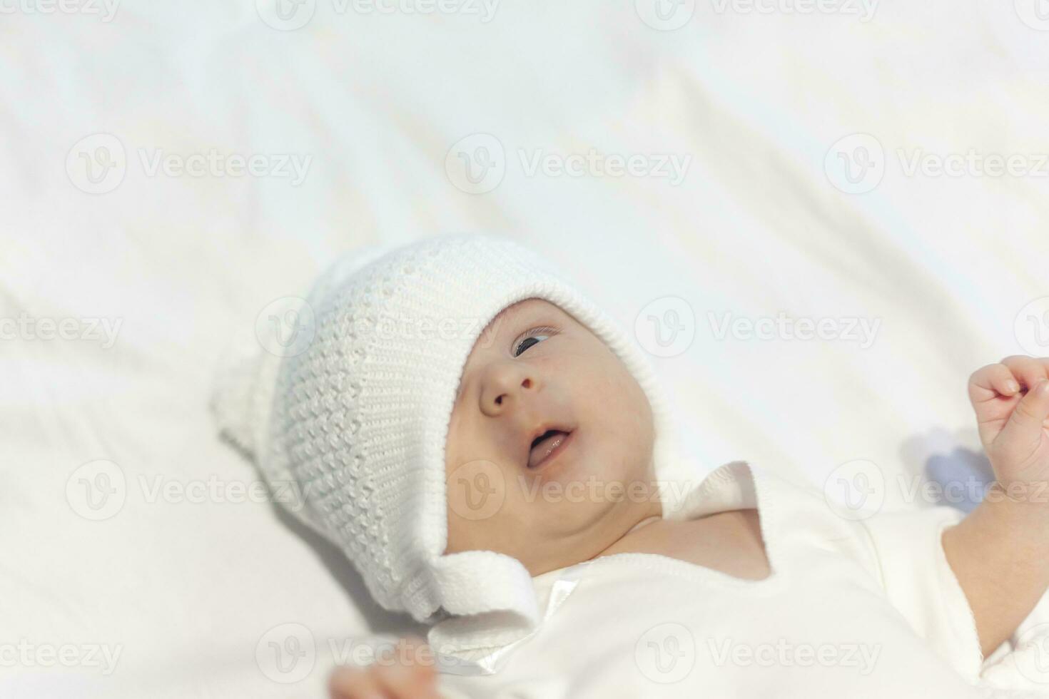 Newborn Baby Boy in Knit Hat Peacefully Lying on white photo