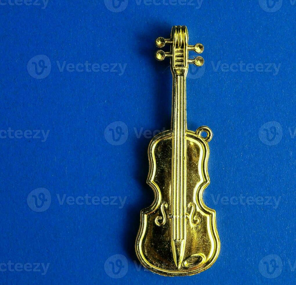 a gold tone violin charm on a blue background photo