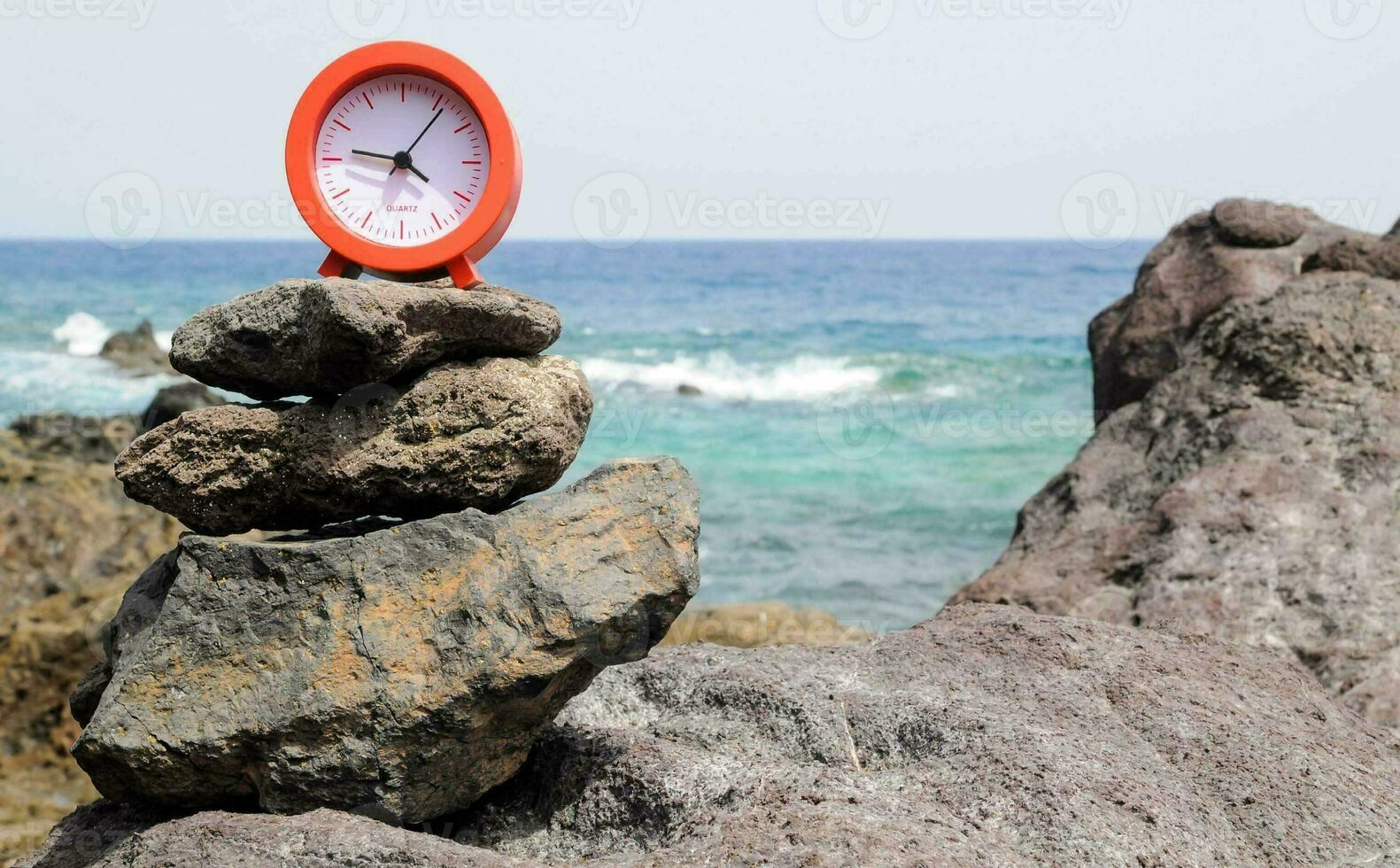 a clock sits on top of a pile of rocks photo