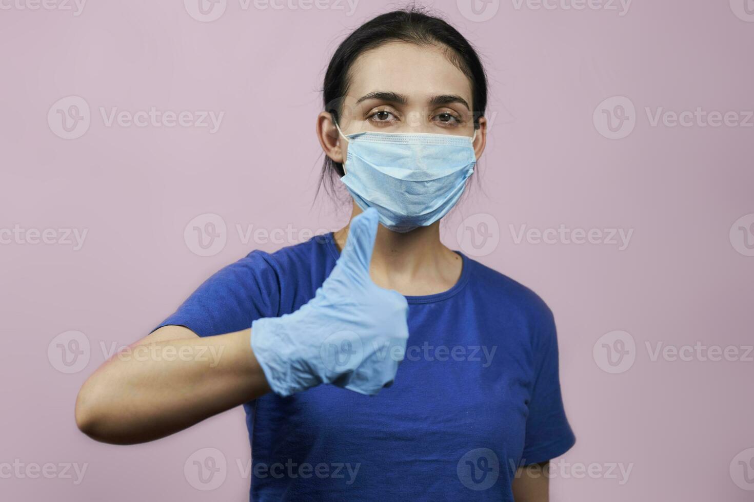 Woman in medical facial mask and protective gloves showing thumbs-up gesture photo