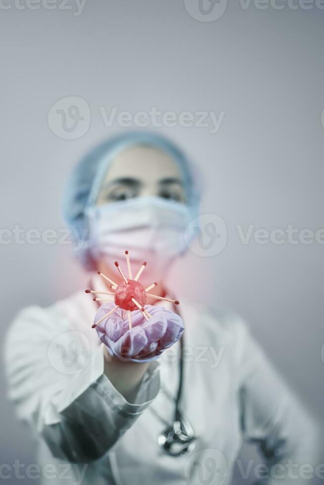 Female doctor in protective medical uniform holding coronavirus photo