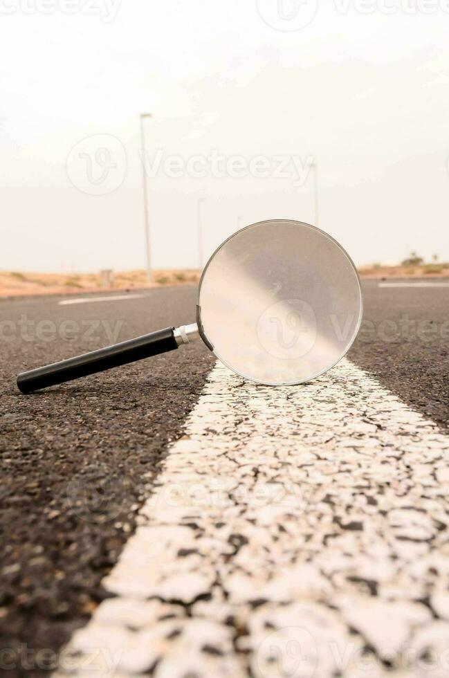 a magnifying glass is laying on the asphalt photo