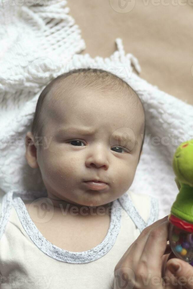 2 month baby boy lying. Close-up of adorable cute newborn baby boy of two months on soft textile. Lovely child playing with plush toy photo