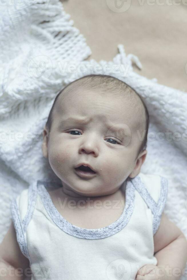 2 mes bebé chico mintiendo. de cerca de adorable linda recién nacido bebé chico de dos meses en suave textil. encantador niño jugando foto