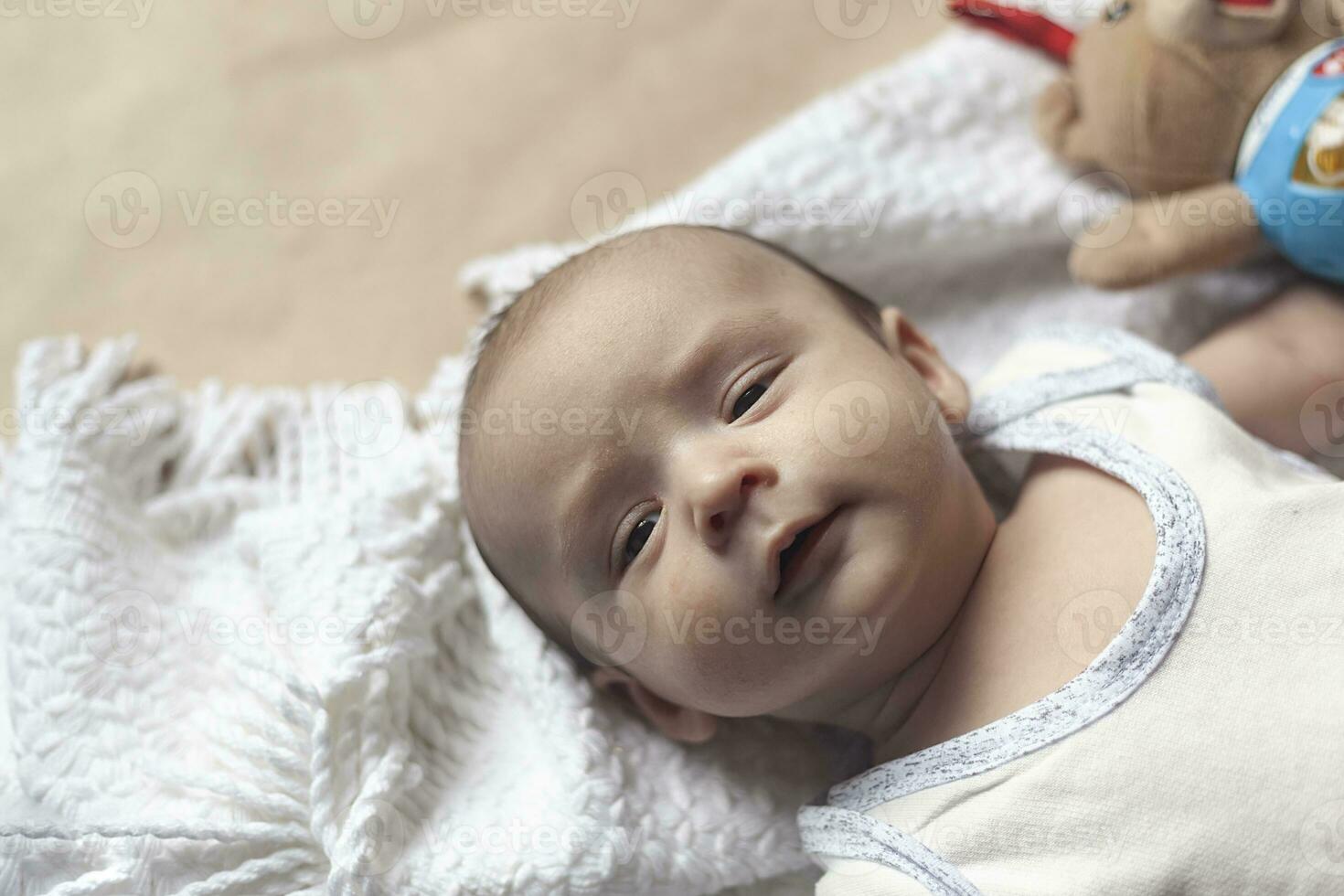 2 mes bebé chico mintiendo. de cerca de adorable linda recién nacido bebé chico de dos meses en suave textil. encantador niño jugando con felpa juguete foto